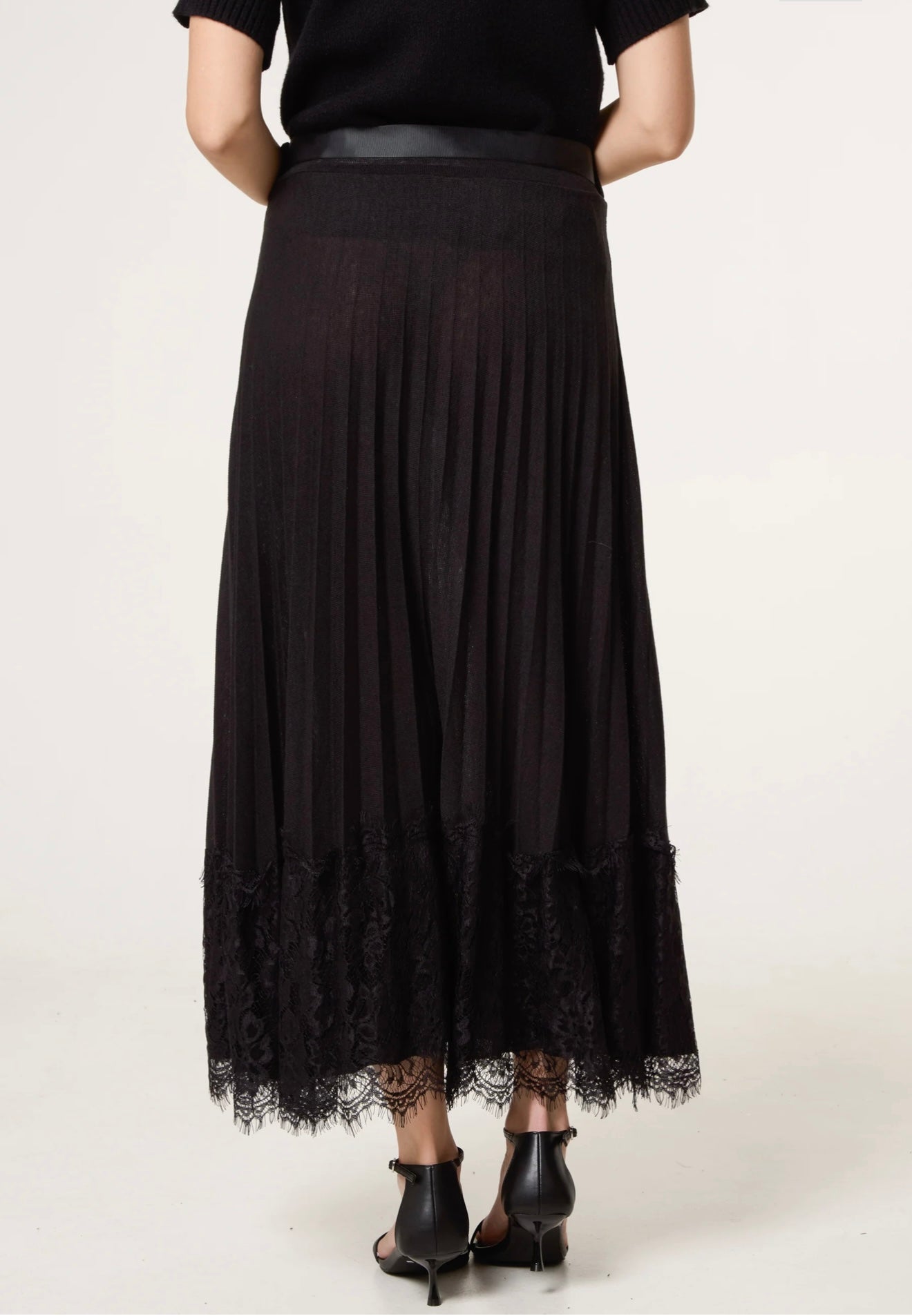Close-up of Notte wool-blend pleated skirt with delicate lace hem — feminine smart-casual design.