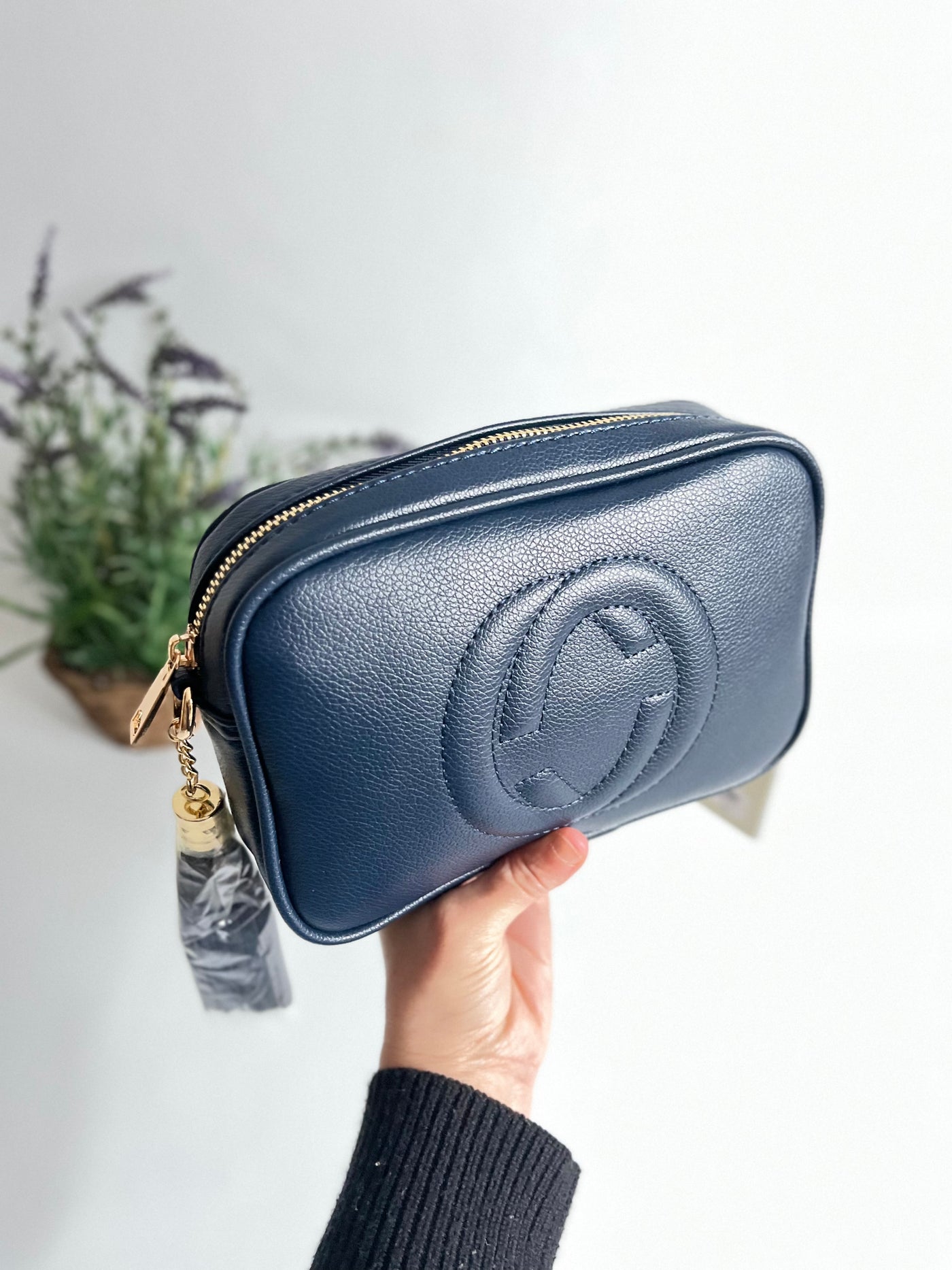 showing details of the zip closure of the navy blue crossbody bag